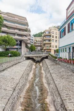 Narrow water stream flowing down through stone paved riverbed built to protec Stock Photos