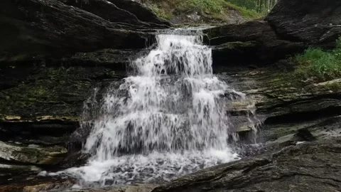 A narrow waterfall cascades over dark Stock Footage 321998332