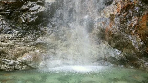 Narrow waterfall collects in a pool in a small rock chasm Stock Footage 248797738