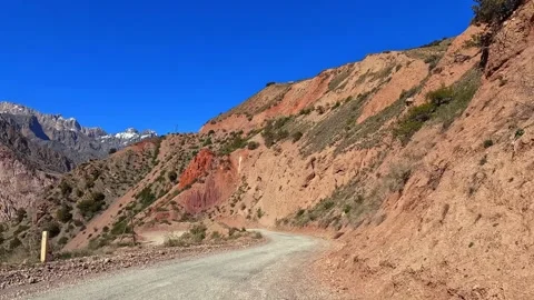 A narrow winding road winds through a rocky mountain pass Stock Footage 317168828