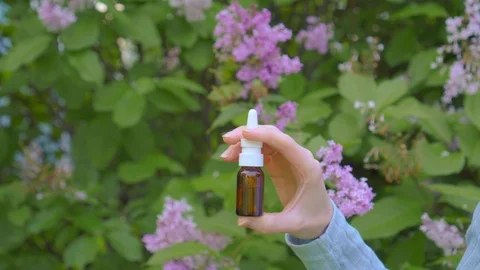 Nasal spray Allergy use on the background of flowering plants Stock Footage 110749325