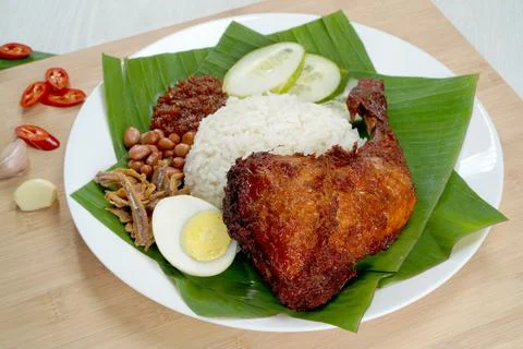 Nasi Lemak dish with chicken drum stick presented on wooden chopping board Stock Photos