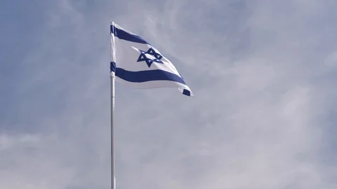 National flag of Israel waving in the wind, with blue sky in the background. Stock Footage