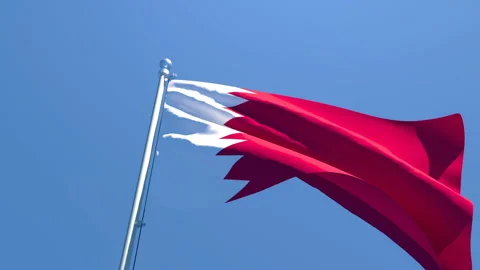 The national flag of Qatar is flying in the wind against a blue sky Stock Footage