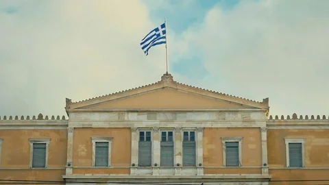 The national Greek flag is developing in the wind on the roof of the building. Stock Footage 84678184
