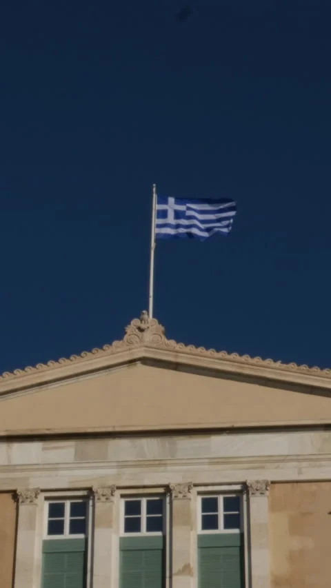 The national Greek flag is developing in the wind on the roof of the building of 動画素材 302080468
