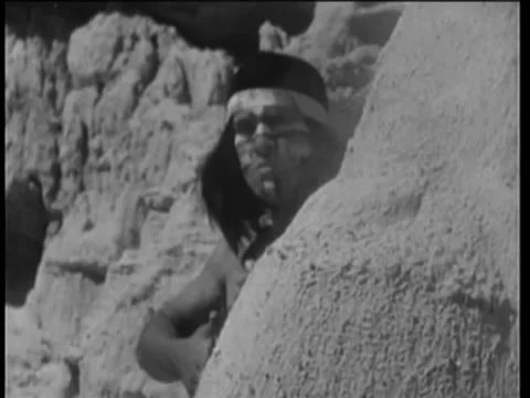 Native American in war paint shooting from behind rock Stock Footage 260240403