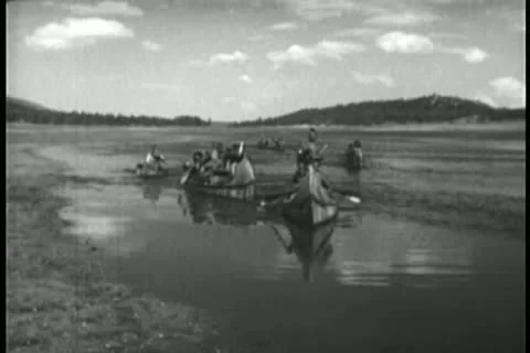 Native Americans paddling down river on canoe Stock Footage