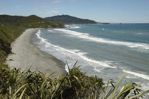 Native bush frames a beach at low tide on a West Coast beach, South Islandrated Stock Photos