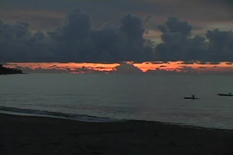 Natives paddle across camera during sunset Stock Footage 286837
