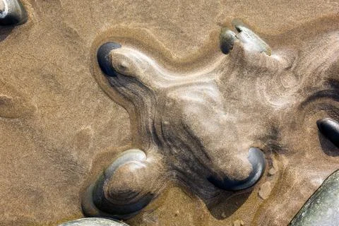 Natural abstract pattern formed by sand over pebbles at low tide Foto stock