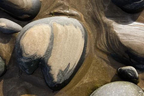 Natural abstract pattern formed by sand over pebbles at low tide Stock Photos