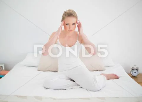 Natural annoyed blonde sitting in bed Stock Photos