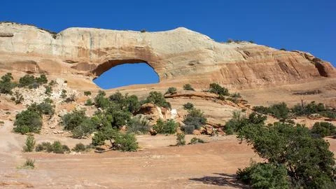 Natural arch formation stands out against a clear blue sky in a rocky lands.. Stock Photos