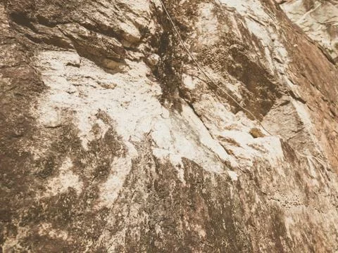 Natural background. Closeup edged shabby cliff cracks. Gray-brown stone rock Stock Photos