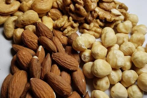 A natural background from different types of nuts is tiled with lots of close Stock Photos