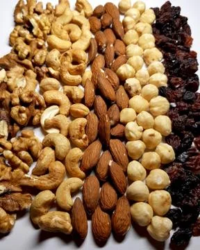 Natural backgrounds of different types of nuts and raisins are lined with row Stock Photos