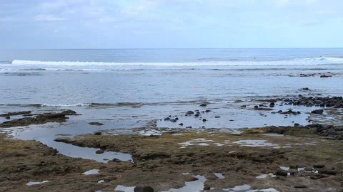 Natural beach with pebbles. In the background some surfers. 1920x1080 HD Video Stock Footage 97939617