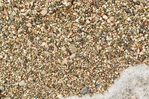 Natural beach texture with tiny stones and gentle surf, ideal for seasonal .. Stock Photos
