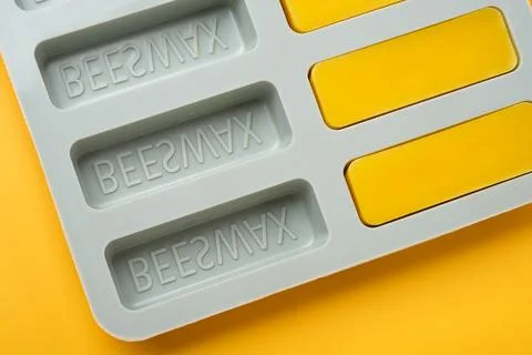 Natural beeswax. Molded bars of beeswax in a silicone mold on a yellow Stock Photos
