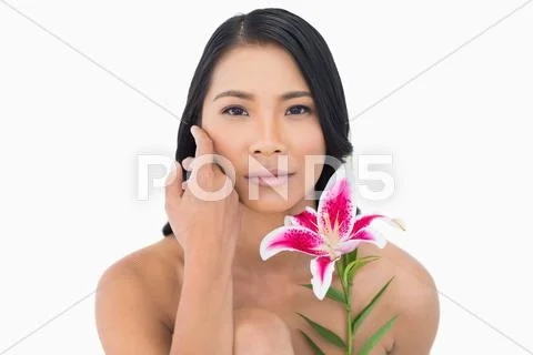 Natural black haired model posing with lily and caressing her face Stock-Fotos