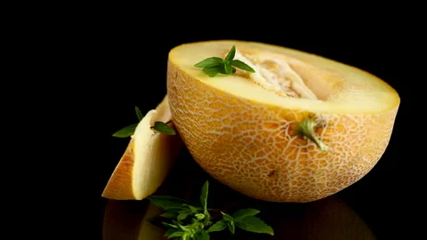 Natural cantaloupe melon composition with basil on reflective black surface Stock Footage 340416135