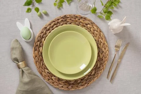 Natural Easter table setting with green plates and wicker placemat Stock Photos