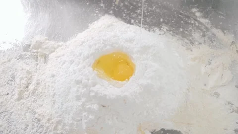 Natural egg falls down on fresh wheat flour on metal table Stock Footage 139486900