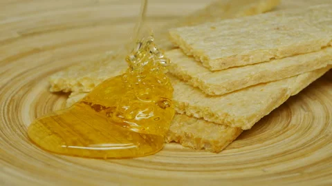 Natural flower honey is poured onto rectangular cornbreads in a cork plate 動画素材 161384664
