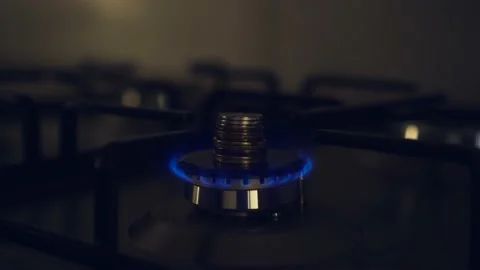 Natural gas is burning weakly in kitchen stove with stack of coins Stock Footage 210225003
