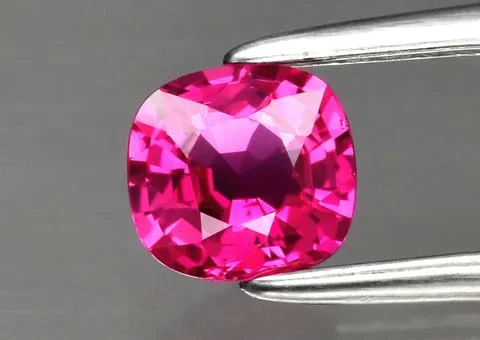 Natural gemstone red ruby in tongs on a gray background 스톡 사진