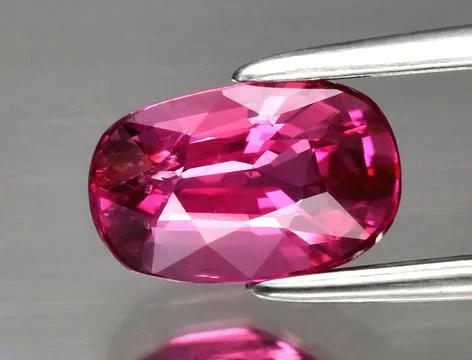 Natural gemstone red ruby in tongs on a gray background 写真素材