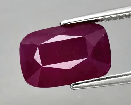 Natural gemstone red ruby in tongs on a gray background Foto stock
