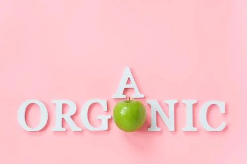 Natural green apple and text Organic from volume white letters on pink backgr Stock Photos