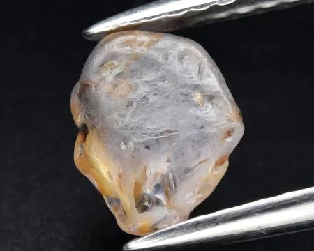 Natural light orange sapphire rough gem on the background Foto stock