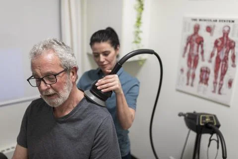 Natural medicine practitioner treating client with shoulder pain Stock Photos