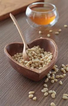 Natural pine nuts in heart shape bowl. Wooden dishes and furniture in kitchen Foto stock