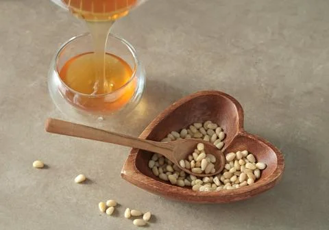 Natural pine nuts in heart shape bowl. Wooden dishes and furniture in kitchen Stock Photos