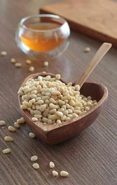 Natural pine nuts in heart shape bowl. Wooden dishes and furniture in kitchen Stock Photos