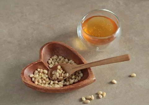 Natural pine nuts in heart shape bowl. Wooden dishes and furniture in kitchen Stock Photos