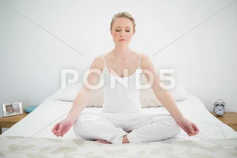 Natural pretty blonde meditating on bed with closed eyes Stock Photos