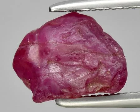 Natural red ruby rough gem on the background Stock Photos
