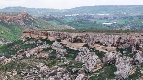 Natural rock arch cuts through a reddish sandstone cliff band on malta a shallow Stock Footage 343582131