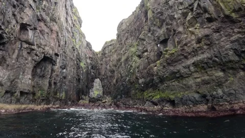 Natural rock arch hidden inside a dramatic basalt sea gorge, Faroe Islands Stock-Footage 339270990