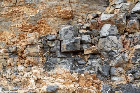 Natural rock texture with sharp grey stones and orange earth layers in a ge.. Stock Photos