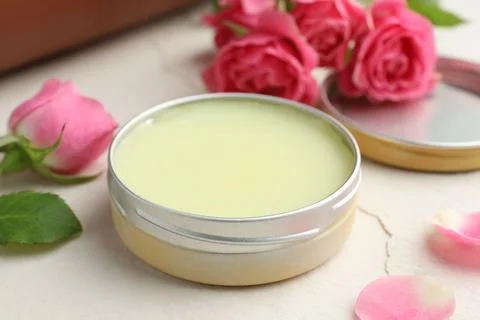 Natural solid perfume in container and pink roses on white table, closeup Stock Photos