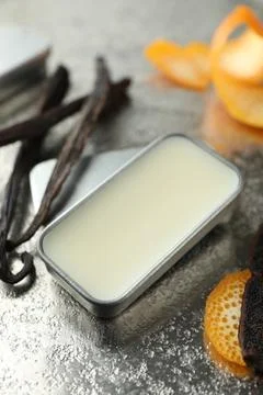 Natural solid perfume in container, vanilla pods and orange peels on grey t.. Stock Photos