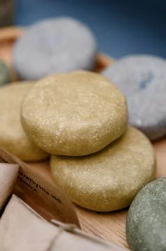 Natural solid shampoo bars in various colors on wooden tray Stock Photos