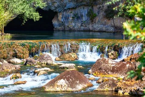 Natural spring flowing from a cavern Stock Photos