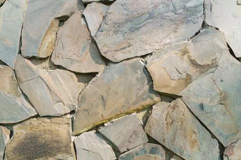 Natural stone wall texture features irregularly shaped slate pieces in earthy Stock Photos